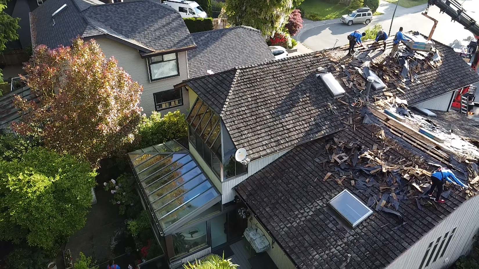 Sierrans Roofing delivering residential roofing service with workers removing old shingles from a house roof